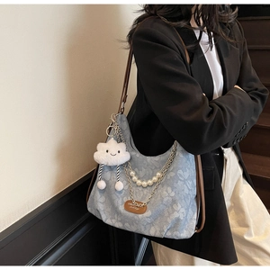 Detail of blue floral canvas tote bag with pearl chain and brown leather shoulder strap