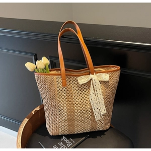 Détail du sac cabas en paille tissée avec nœud en dentelle et anses en cuir