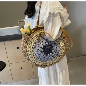 Detailed macro view of woven floral pattern and leather strap on straw tote bag