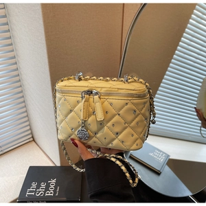 Detail of yellow quilted box bag with rhinestone accents and silver camellia charm