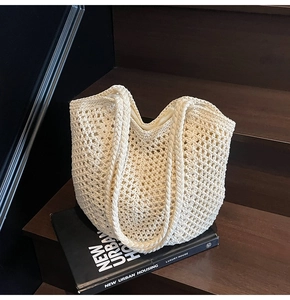 Close-up of cream woven tote bag on wooden steps with textured mesh knit detail