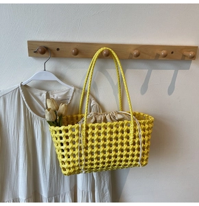 Detail van gele gevlochten emmerstas met lange hengsels en een beige trekkoord voering