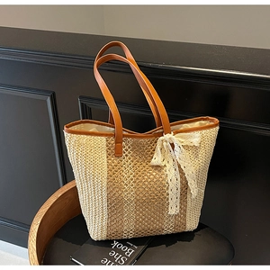 Détail du sac cabas en paille tissé avec anses en cuir marron et nœud en dentelle