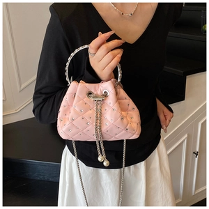Detail of pink quilted bucket bag with rhinestones, chain drawstring and pearl charm
