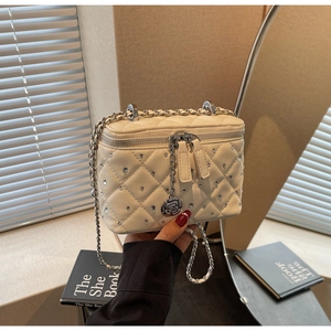 Detail of white quilted box bag featuring crystal studs and silver floral charm