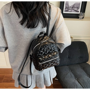 Close-up of quilted black mini backpack with rhinestones worn by a model in interior setting