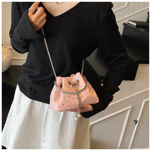 On-body shot of a pink quilted bucket bag with rhinestones and pearl drawstring detail