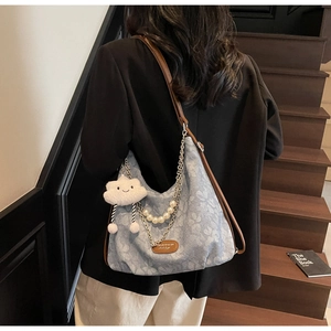 Detail of light blue floral canvas shoulder bag with pearl chain and cloud charm