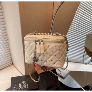 Close-up of quilted cream vanity bag with sparkling crystal decor and rose charm