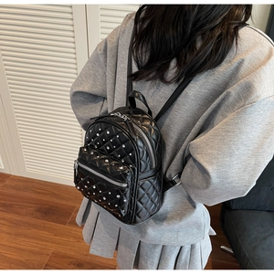 Mini black quilted backpack with diamond stitching and rhinestone details shown on model