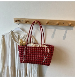 Detail van een rode gevlochten tote bag met een crèmekleurige canvas binnenvoering