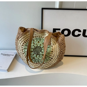 Close-up of bohemian woven straw tote bag with round sunflower pattern and leather straps