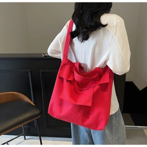 Side view of large red canvas tote bag with ruffle pockets shown on a model