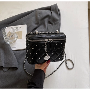 Close-up of black quilted box bag with silver studs and camellia pendant detail