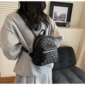 Close-up of a black mini quilted backpack with sparkling rhinestone studs on a model