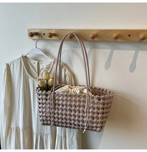 Detailopname van geweven shopper met beige trekkoordvoering aan een houten haakje
