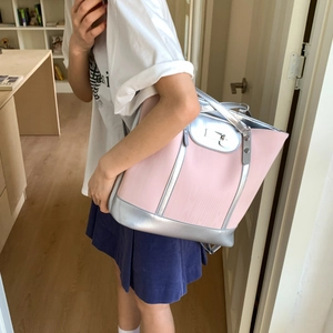 Detail of pink and silver tote bag with decorative lock shown in a casual home setting