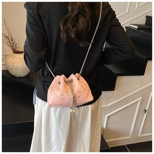 Crossbody view of pink quilted bucket bag with rhinestones and pearl drawstring charms