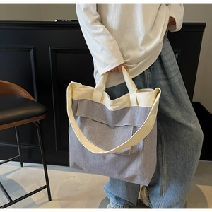 Detail of blue striped canvas tote with cream straps and large front pocket for daily use