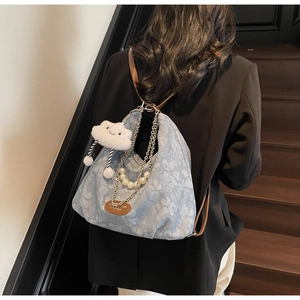 Detail of light blue hobo bag with pearl chain, floral pattern and plush cloud charm