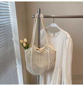 Detail of crochet tote bag with hollow mesh texture, cream inner lining and braided strap