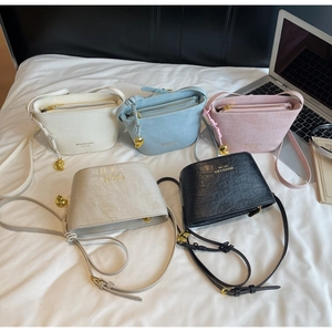 Detail of five mini bucket bags in pastel colors with crocodile pattern and heart charms
