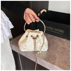 Close-up of cream quilted bucket bag with rhinestone accents and metallic ring handle