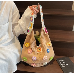 Detail of handmade crochet hobo bag featuring colorful 3D knitted flowers and woven strap