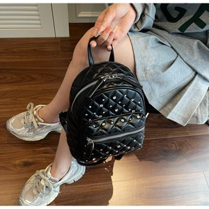 Close-up of quilted black leather mini backpack with sparkling rhinestone embellishments