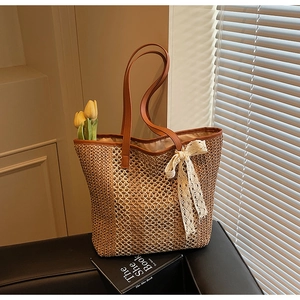 Détail du sac cabas en paille avec nœud en dentelle blanche et bandoulières en cuir brun