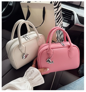 Close-up of lychee grain leather boston bags with silver dolphin charm on car seat