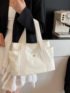White canvas tote bag for women featuring a large front pocket and vintage metal button