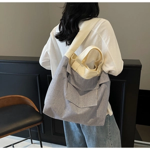Detail of a large striped canvas tote bag with a minimalist shoulder strap and wide pocket