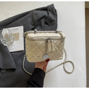 Detailed macro of quilted leather box bag featuring silver rhinestones and camellia charm