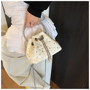 Detail of white quilted bucket bag featuring shiny rhinestones and metal ring handle