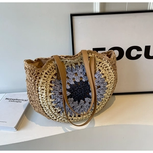 Detailed close-up of straw tote bag with crochet floral patterns and leather handles