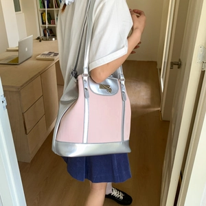 Detail of pink and silver tote bag featuring heart pendant and metallic clasp