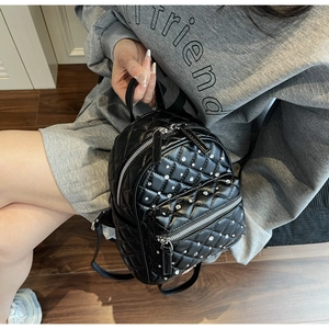 Close-up of black quilted mini backpack with rhinestone details and silver metallic zippers
