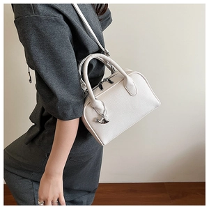 Detail showing white lychee pattern leather bowling bag with silver dolphin charm detail