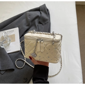 Detail of cream quilted crossbody bag with silver rhinestones and flower charm