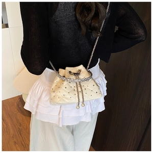 Detail of cream bucket bag with quilted diamonds, rhinestones, and pearl chain strap