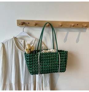Detail van groene gevlochten shopper met roosterontwerp en witte binnentas met trekkoord