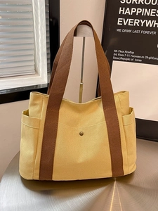 Minimalist beige canvas tote bag with brown woven handles and practical side pockets