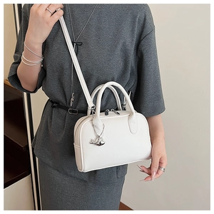 Detail of white lychee grain leather handbag with silver whale pendant on a female model