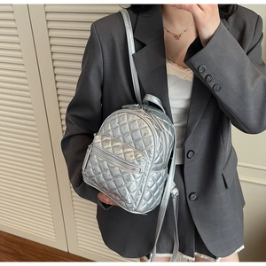 Silver quilted mini backpack with metallic finish and metal studs shown on model