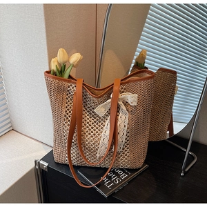 Détail d'un sac cabas tressé avec un nœud en dentelle blanche et des anses en cuir marron