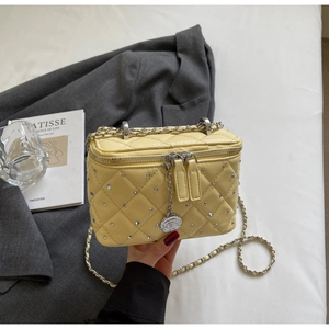 Detail of yellow quilted box bag with silver studs and rose pendant accessory