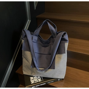 Detail of canvas tote bag with black and white gingham pattern on wooden stairs