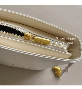 Detailed close-up of smooth gold zipper and crocodile pattern on white bucket bag