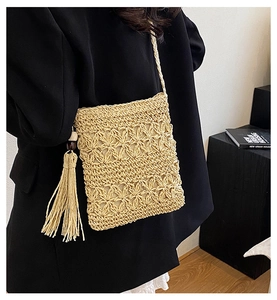 Detail of handmade woven straw crossbody bag with floral texture and tassel